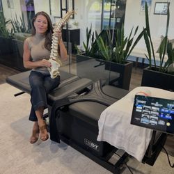 Cherine Reid - Health First Chiropractic & Wellness - Dr. Cherine Reid showing a spine model on HillDT Spinal Decompression Table