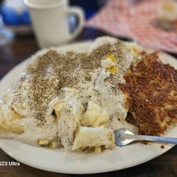 Jimmy's Round-Up Cafe & Fried Pies - Biscuit Debris covered in black pepper! There are two over easy eggs, diced ham, cheddar cheese, and sausage under the gravy.