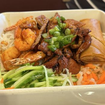 Pho Minh - 87. Bún Thập Cẩm - A Vietnamese meal featuring shrimp, grilled meat, shredded vegetables, and a spring roll in a takeout box. - Soup Near Me - Temecula, California
