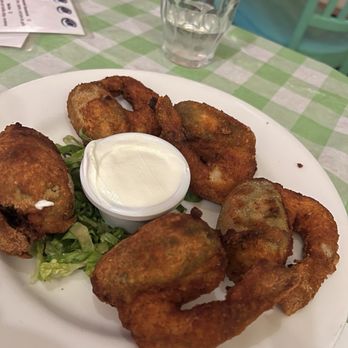 Armadillo - Fried calamari rings with a small container of dipping sauce are served on a white plate, with lettuce underneath, at a restaurant with a checkered tablecloth. - Mexican Near Me - Kingston, New York