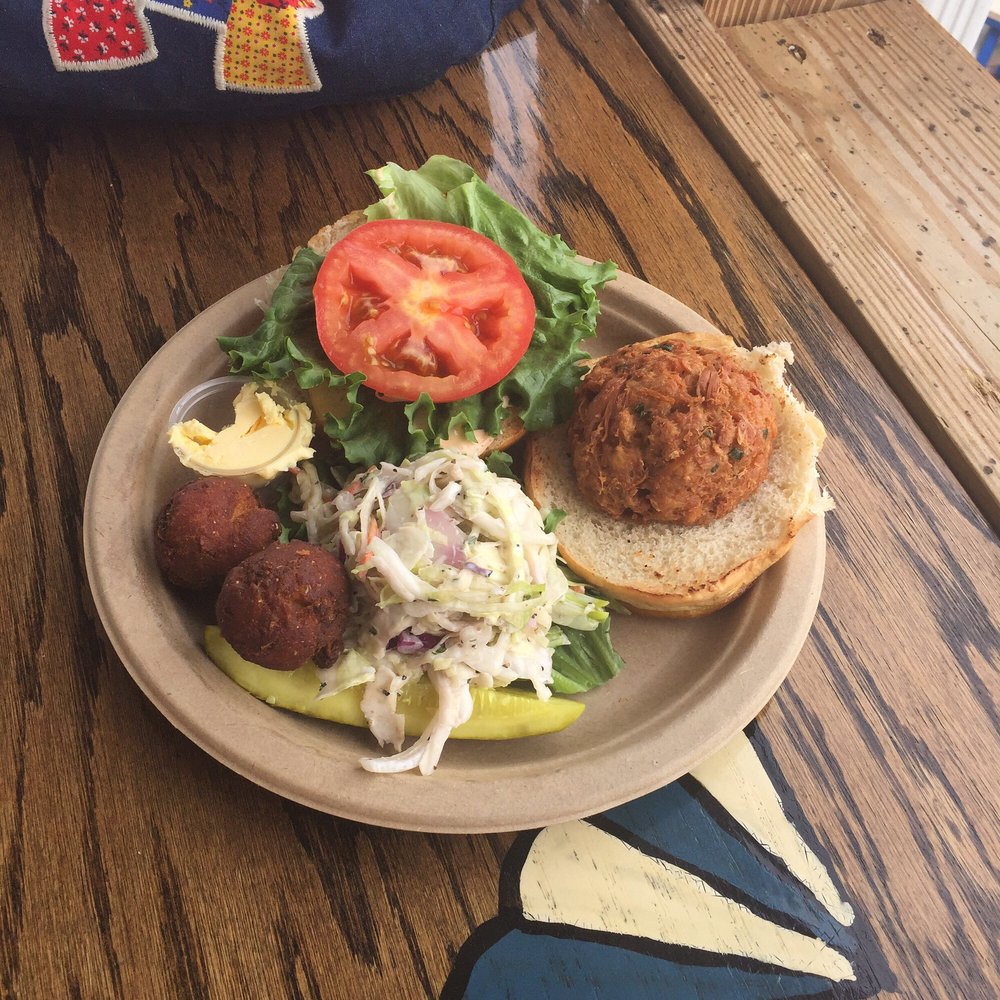 Fried crab cake sandwich with slaw, pickle, and hush puppies with honey