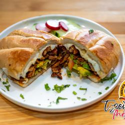 Trocitos De Mexico - Torta Al Pastor stacked with tender, marinated pork straight off the trompo, caramelized pineapple, creamy avocado, fresh cilantro, & more