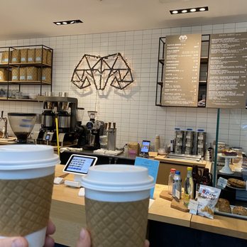 Kohi Coffee Company - a person holding two cups of coffee - Coffee & Tea Near Me - Boston, Massachusetts