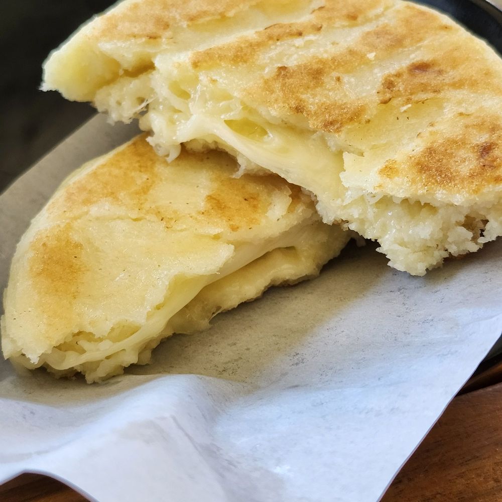 Hot cheese arepa. Flaky outside, gooey, cheesy inside. Comes with two dipping sauces.