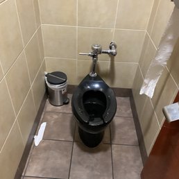 a toilet and trash can in a public restroom
