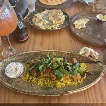 Oria - Salmon pizza, hummus that we devoured prior to pic. Almost gone bread lol. Chicken skewers with rice... - Mediterranean Near Me - Austin, Texas