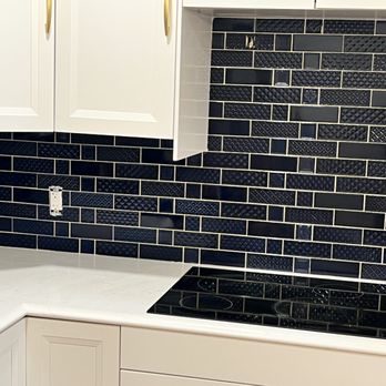AM Lopes Flooring - a kitchen with white cabinets and a black tile backsplash - Flooring Near Me