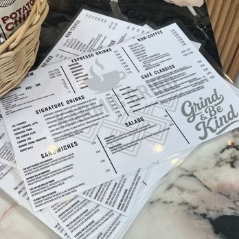 Karmic grind - A printed menu featuring coffee, espresso drinks, non-coffee beverages, salads, and sandwiches, placed on a marble surface in a cafe setting. - Coffee & Tea Near Me - Locust Valley, New York