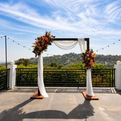 Tlapazola Event Rentals - Elegant wedding ceremony arch setup overlooking the Hollywood Hills with floral arrangements and romantic outdoor event styling.