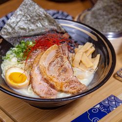 Zuru Ramen Bar - Tonkotsu Ramen features a rich, creamy pork bone broth with tender noodles, pork chashu, scallions, and a soft-boiled egg.