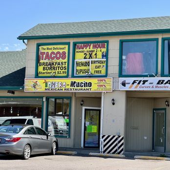 Takero Mucho - Front of building - A two-story building houses a Mexican restaurant with signs for tacos, breakfast, and happy hour, along with a fitness bar sign. - Mexican Near Me - Aurora, Colorado