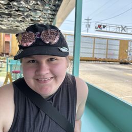 Woman sitting at ice cream bar with train in background Woman sitting at ice cream bar with train in background