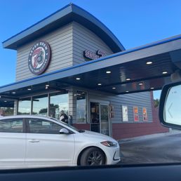 Seven Brew - A Seven Brew Coffee drive-thru storefront with a white car parked in front, under a clear blue sky.