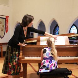 The Music Room - Miss Jessica guides a student as she plays in the winter recital.