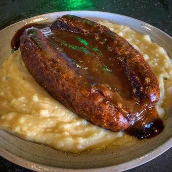 Mickey Quinns - BANGERS ANO MASH Sizzling traditional Irish sausages over creamy mashed potatoes finished with caramelized onions and rich gravy. - Irish Pub Near Me - Seminole, Florida Mickey Quinns - BANGERS ANO MASH Sizzling traditional Irish sausages over creamy mashed potatoes finished with caramelized onions and rich gravy. - Irish Pub Near Me - Seminole, Florida