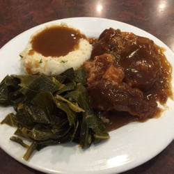 Smothered pork chop with mashed potatoes and greens