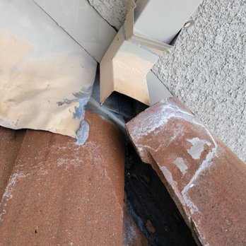Hernandez's Roofing - Before. Downspout pouring rain underneath roof tiles. - Roofing Near Me