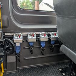 RideToo - Four retractors for every mobility device, always. Seen here, hung neatly, ready for our next ride: Easy for drivers, clean for safety.