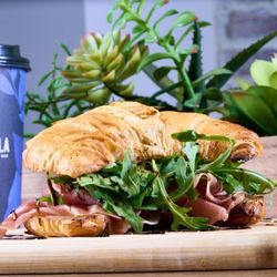 Carmela Coffee - Pompano Beach - Prosciutto & Swiss croissant at Carmela Coffee Pompano with a buttery croissant, prosciutto, Swiss cheese, arugula, and balsa...