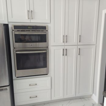 Maxi Serve Restoration & Construction - a kitchen with white cabinets and stainless steel appliances - General Contractors Near Me