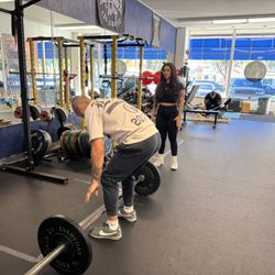 A-Team Health and Fitness - Coach Tori assisting with a deadlift. Coach Tori is a certified body transformation specialist with power workouts.