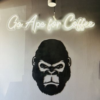 Ape Coffee - A neon sign displaying 'Go Ape for Coffee' is mounted on a wall, with a gorilla face mural below it, in a coffee shop setting. - Cafes Near Me - Placentia, California