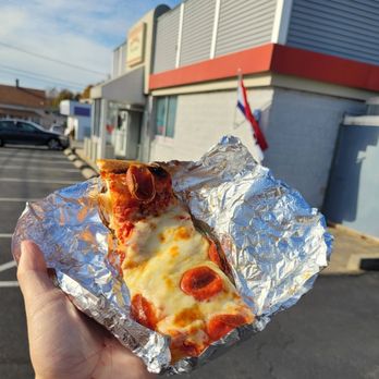 DePetrillo's Pizza & Bakery - a hand holding a piece of pizza - Pizza Near Me - North Providence, Rhode Island DePetrillo's Pizza & Bakery - a hand holding a piece of pizza - Pizza Near Me - North Providence, Rhode Island