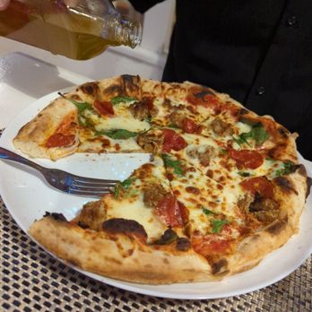 Rubini's Pizzaria - Moda da Casa pizza being drizzled with chili oil - Italian Near Me - Luz, 08
