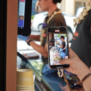 Gelatissimo Waikiki - a woman taking a picture of a man on a cell phone - Gelato Near Me - Honolulu, Hawaii Gelatissimo Waikiki - a woman taking a picture of a man on a cell phone - Gelato Near Me - Honolulu, Hawaii