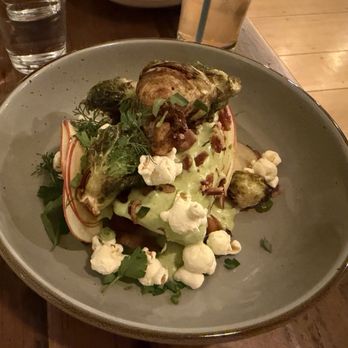 Linden + Front - Radicchio wedge salad with yummy green goddess dressing (TIP: Ask for a steak knife because the radicchio is a bit hard to cut through.) - A plate of roasted vegetables topped with green sauce, popcorn, and herbs, served on a gray dish at a restaurant. - New American Near Me - Bath, Maine