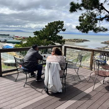 Four Fools Winery - two people sitting at a table on a deck overlooking the ocean - Wineries Near Me - Rodeo, California