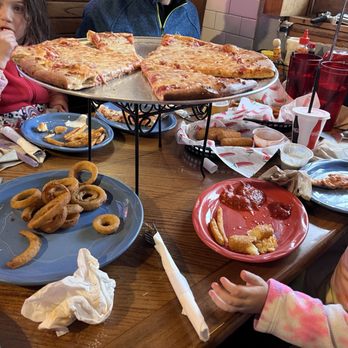 Magustos - a group of people sitting at a table with a pizza - Pizza Near Me - Minturn, Colorado