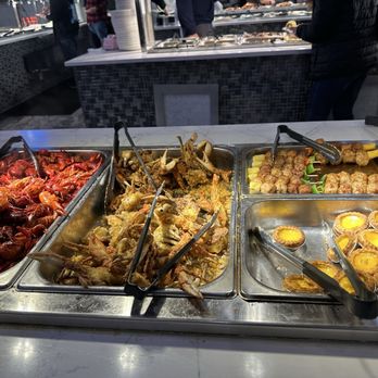 Number 1 Buffet - A buffet setup featuring cooked crawfish, fried seafood, skewers, and egg tarts in stainless steel trays at a restaurant. - Buffets Near Me - Avondale, Arizona