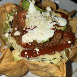 Amigos Taqueria Y Tequila - Tijuana Taco Salad - ground beef, cheddar cheese, tomato, black beans, avocado- taco shell w/ sour cream & amigos taco sauce $18