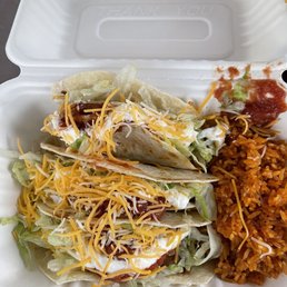 a white styrofoam container filled with tacos and rice a white styrofoam container filled with tacos and rice