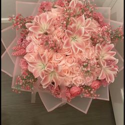 Hey Flower Lady International Floral Distributors - A bouquet of pink lilies, pink roses, and small white flowers wrapped in pink paper.