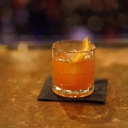 a glass of orange drink on a coaster