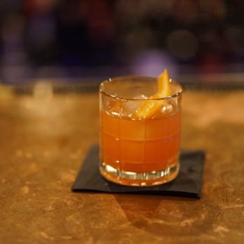 Stateroom Bar - a glass of orange drink on a coaster - Cocktail Bars Near Me - Laguna Beach, California