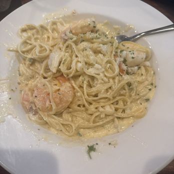 Mama's on the Half Shell - Alfredo with crab and shrimp - A white plate contains seafood pasta with a creamy sauce, shrimp, and lobster pieces, garnished with herbs, served at a restaurant. - Bars Near Me - Baltimore, Maryland