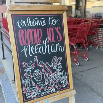 Trader Joe's - A chalkboard sign with colorful lettering and illustrations is placed outside Trader Joe's in Needham, MA, welcoming customers. - Grocery Near Me - Needham, Massachusetts
