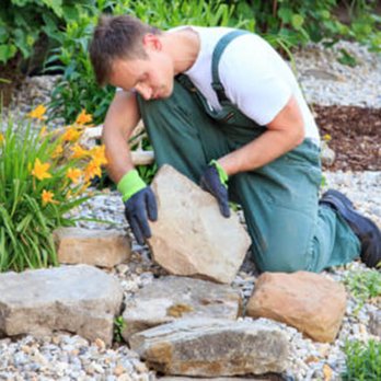 Aguilar Lopez Landscaping Services - a man placing a rock into a garden bed - Landscaping Near Me Aguilar Lopez Landscaping Services - a man placing a rock into a garden bed - Landscaping Near Me