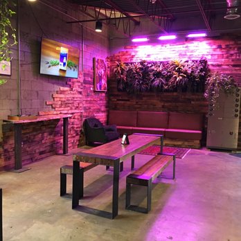 Safe House Distilling - a table and bench in a dimly lit room - Bars Near Me - Albuquerque, New Mexico