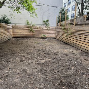 Onafastpace Contracting - What they were starting with. - An outdoor backyard space with bare soil ground, enclosed by a horizontal wooden fence, and some small plants and trees. - Artificial Turf Near Me