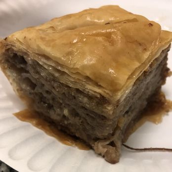 Athens Bakery - Baklava - A close-up of a square piece of baklava showing layered phyllo dough and a nut filling, topped with a shiny glaze. - Bakeries Near Me - Teaneck, New Jersey