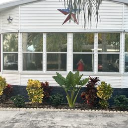 windows tinted - A white building with large windows, purple shutters, and patriotic star decorations on the exterior, with a landscaped garden in front.