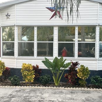 Jonathan Window Tint - windows tinted - A white building with large windows, purple shutters, and patriotic star decorations on the exterior, with a landscaped garden in front. - Home Window Tinting Near Me - Boca Raton, Florida