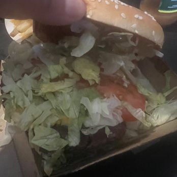 McDonald's - a hand holding a hamburger with lettuce and tomatoes - Burgers Near Me - Arvin, California
