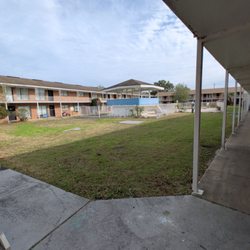 Harmoni Home Services - Apartment complex courtyard with grassy lawn, fenced swimming pool, and gazebo pavilion...