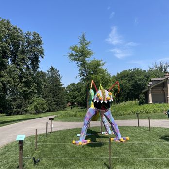 Cantigny - A vibrant, large insect sculpture with multiple colors and patterns is situated on a grassy area at Cantigny Park, surrounded by a low rope barrier. - Museums Near Me - Wheaton, Illinois