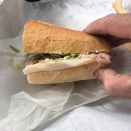 a hand holding a sub sandwich